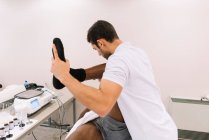 Il fisioterapista che tratta un uomo usando attrezzature per la radioterapia — Foto stock