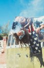 Mujer morena con bengala y bufanda americana en la vieja furgoneta - foto de stock