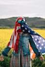 Леди в повседневной одежде в желтом поле в солнечных очках над американским флагом с солнечным светом — стоковое фото