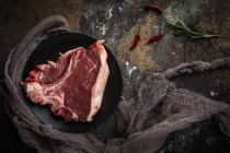 Raw beef steak on black plate on dark stone background — Stock Photo