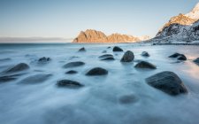 Pietre scure lisce in lungo flusso di esposizione di acqua sullo sfondo di scogliere, Lofoten, Norvegia — Foto stock
