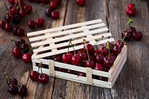 Caja de madera de deliciosas cerezas maduras sobre madera marrón - foto de stock