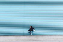 Uomo che salta contro il muro di metallo blu sulla strada della città — Foto stock