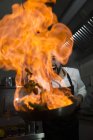 Excited cook making a flambe in restaurant kitchen — Stock Photo