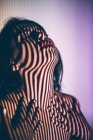 Jeune femme séduisante seins nus avec lèvres rouges et ombre rayée sur le visage et le corps posant en studio — Photo de stock
