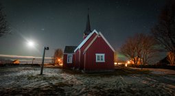 Червона дерев'яна каюта в засніженій долині вночі — стокове фото