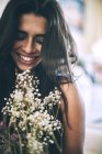 Молода усміхнена жінка з закритими очима позує з квітами — стокове фото