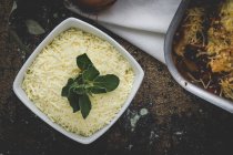 Печеные макароны с сыром и чоризо в сковороде и тертый сыр в миске — стоковое фото