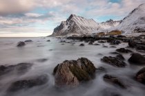 Rocce lisce nel flusso di acqua e montagne rocciose innevate sullo sfondo — Foto stock