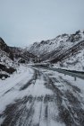 Abgelegene kalte Fahrbahn in verschneiten dunklen Bergen — Stockfoto