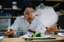 Шеф-повар готовит в ресторане с блюдом из дыма — стоковое фото