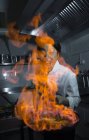 Cocinero emocionado haciendo un flambe en la cocina del restaurante - foto de stock