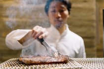 Cocinero cocinando en restaurante preparando carne asada - foto de stock
