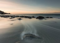Smooth rocks in flow of water under sunset sky — Stock Photo