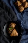 Croissants cuits au four dans un plat et sur une assiette en tissu noir — Photo de stock
