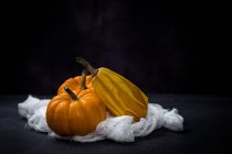 Fresh pumpkins on white cloth on black background — Stock Photo