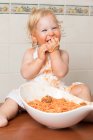 Bambino allegro seduto sul racconto e divertirsi mentre si mangia la pasta dalla ciotola. — Foto stock
