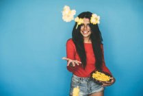 Young woman standing and throwing flowers on blue background — Stock Photo