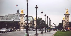 Puente Alejandro III con linternas en fila y estatuas cubiertas de oro sobre el fondo del Grand Palais. París, Francia - foto de stock