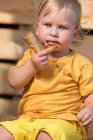 Giovane ragazzo in abiti gialli mangiare gelato al cioccolato con cono waffle. — Foto stock