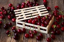 Caixa de madeira de deliciosas cerejas maduras em madeira marrom — Fotografia de Stock