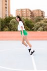 Mujer joven en ropa deportiva cayendo hacia adelante directamente en el campo de deportes al aire libre en la ciudad - foto de stock