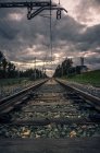 Вид на залізничну дорогу, що втікає в сільській місцевості з темними похмурими хмарами вище — стокове фото