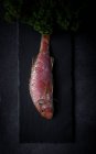 Manojo de perejil y salmonete rojo crudo sobre pizarra negra - foto de stock