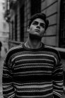 Joven adolescente confiado en suéter de pie en la calle de la ciudad y mirando hacia arriba - foto de stock
