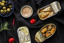 Ciotola con olive e varie conserve di pesce e frutti di mare su panno nero — Foto stock