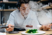 Chef cocinando en restaurante con plato de humo - foto de stock