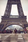 Basement of Eiffel Tower crowded by tourists on background of cityscape, Paris, France — Stock Photo