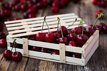 Close-up of wooden box of delicious ripe cherries on brown wood — Stock Photo