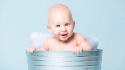 Cheerful nude toddler boys sitting in metallic buckets with pillows. — Stock Photo