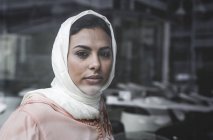Porträt einer nachdenklichen marokkanischen Frau mit Hijab, die hinter einer Fensterscheibe sitzt — Stockfoto