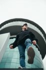 Young man standing on background of modern building and stepping down — Stock Photo