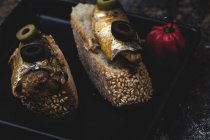 Скибочки хліба з консервованою рибою та оливками на сковороді біля гострого перцю — стокове фото