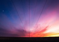 Wires of power line under amazing multicolored sky — Stock Photo