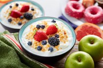 Сніданок з йогуртом та ягодами на столі з інгредієнтами — стокове фото