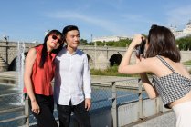 Woman taking photo of Asian couple — Stock Photo