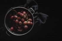 Fresh red grapes in pot on black background — Stock Photo