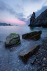 Pedras ásperas na costa perto da calma água do mar ao pôr do sol, Astúrias, Espanha — Fotografia de Stock