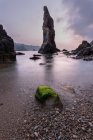 Rough rocks on shore near calm sea water at sunset, Asturias, Spain — Stock Photo