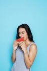 Jeune femme en body manger pastèque sur fond bleu — Photo de stock