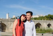 Schöne asiatische Frau stützt sich auf die Schulter eines hübschen Mannes, während sie an einem sonnigen Tag zusammen im wunderschönen Park steht — Stockfoto