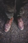 Beine von Reisenden in schmutzigen Stiefeln stehen auf Asphaltstraße — Stockfoto