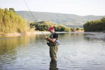 Homem em pé na água e na pesca — Fotografia de Stock