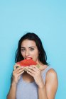 Portrait de jeune femme mangeant pastèque sur fond bleu — Photo de stock