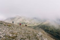 Gruppo di viaggiatori che camminano lungo il crinale della montagna il giorno nebbioso — Foto stock