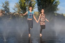 Asiatico donne jumping su fontana acqua — Foto stock